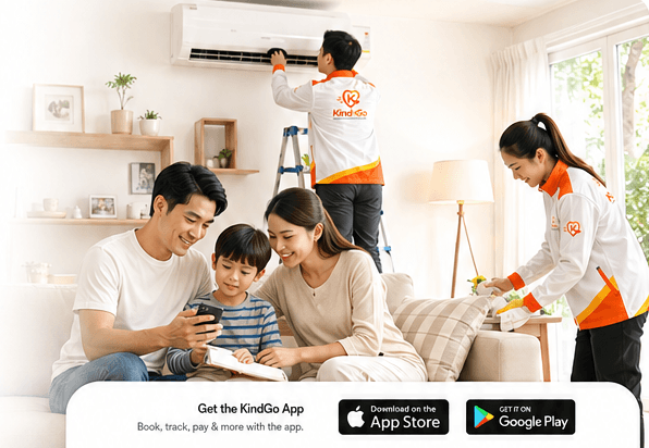 A family relaxing at home while KindGo professionals install an aircon and tidy the living room. Bottom bar: Get the KindGo App — Book, track, pay & more with the app, with App Store and Google Play badges.