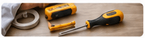 Hand tools including a screwdriver and tape on a wooden bench